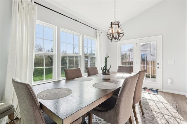 dining room featuring lofted ceiling, a notable chandelier, wood finished floors, and plenty of natural light