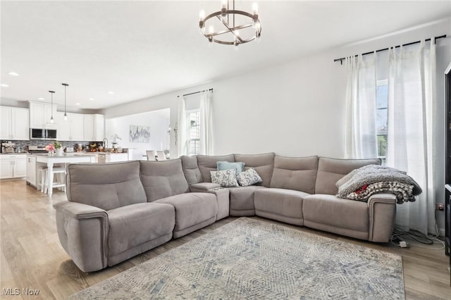 living room featuring light wood-style flooring, an inviting chandelier, and recessed lighting