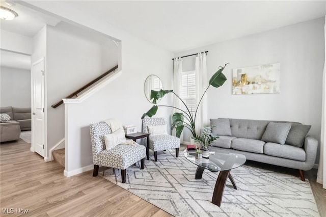 living room with stairway, baseboards, and light wood-style floors