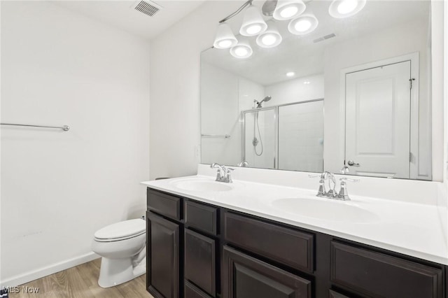 full bathroom featuring a shower stall, wood finished floors, a sink, and visible vents