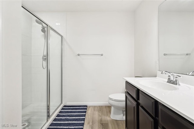 full bath with wood finished floors, toilet, vanity, baseboards, and a stall shower