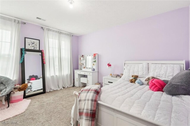 bedroom featuring visible vents and light colored carpet