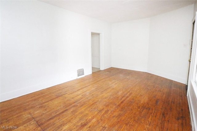 spare room featuring hardwood / wood-style floors and visible vents