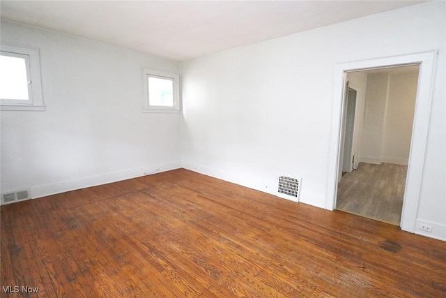 spare room featuring baseboards, wood finished floors, and visible vents