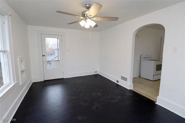 empty room featuring arched walkways, baseboards, visible vents, wood finished floors, and ceiling fan