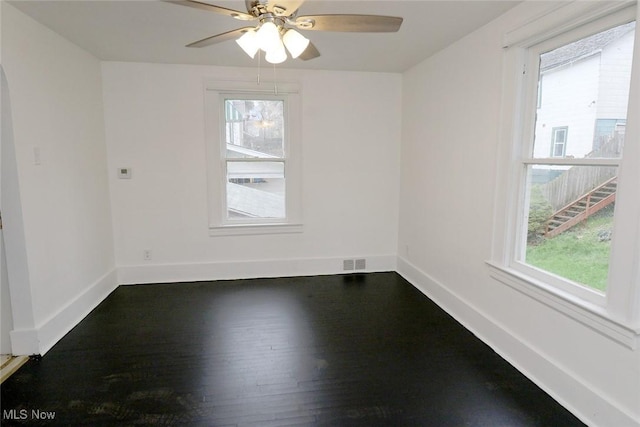 empty room with a healthy amount of sunlight, baseboards, and dark wood-style flooring