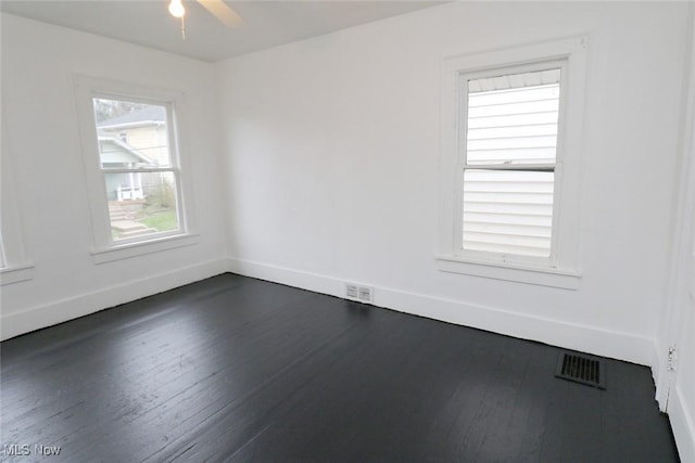 spare room featuring dark wood-style floors, baseboards, a ceiling fan, and visible vents