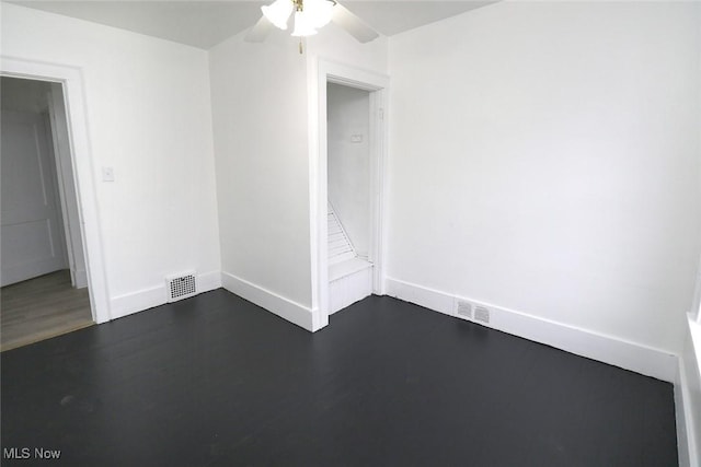 spare room featuring dark wood-style floors, baseboards, a ceiling fan, and visible vents