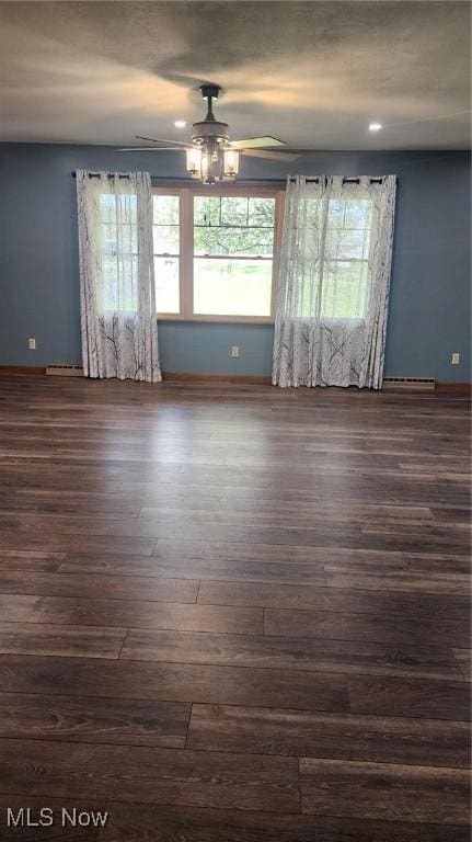 empty room with a ceiling fan, baseboards, and dark wood-type flooring