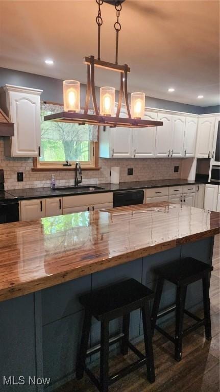 kitchen with white cabinets, butcher block counters, black appliances, and a sink