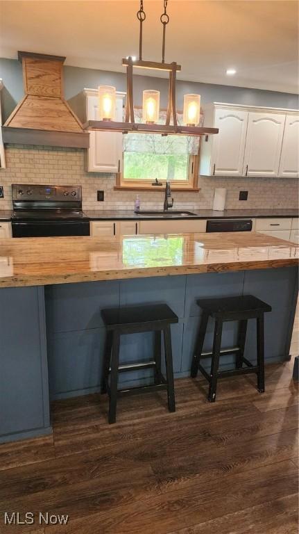 kitchen featuring wood counters, custom exhaust hood, a sink, and black range with electric cooktop