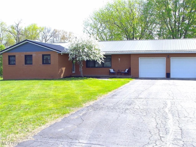 ranch-style home with brick siding, an attached garage, aphalt driveway, and a front yard