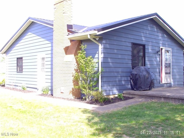 view of side of home featuring a yard and a chimney