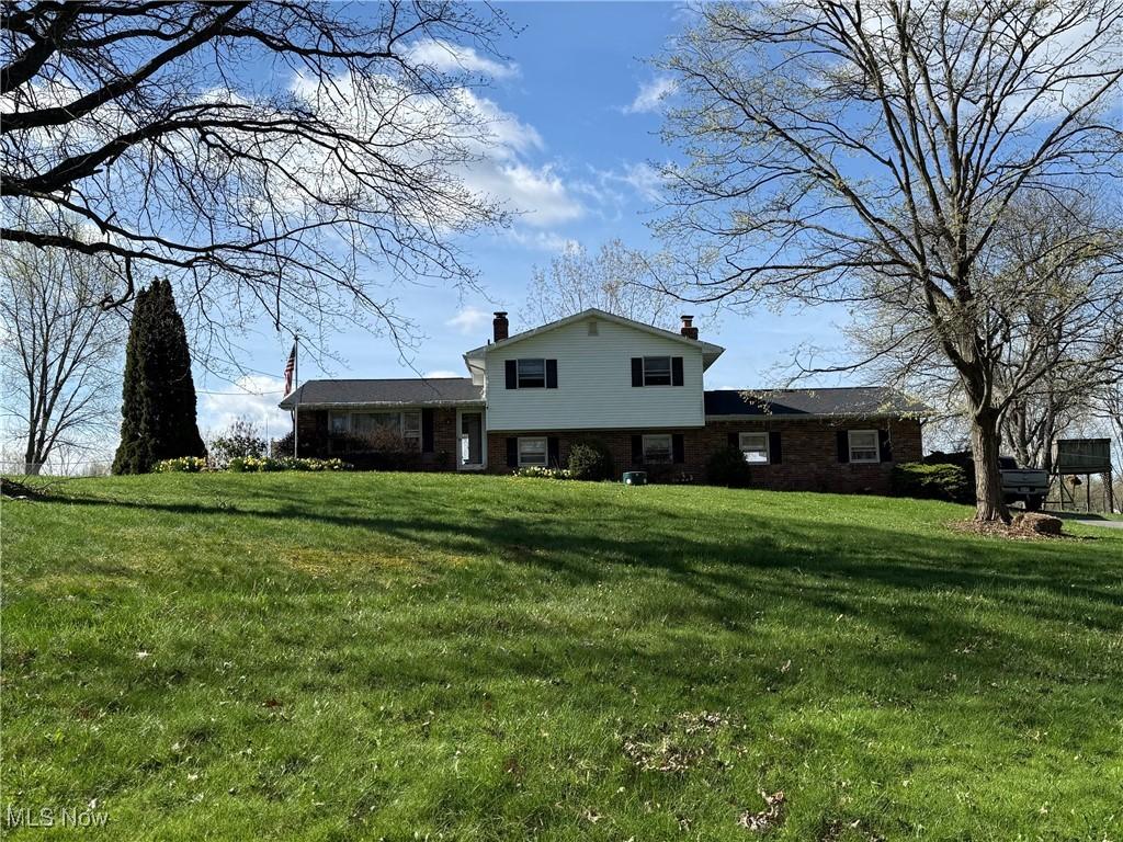 8754 NE Lynnett St NE, Alliance, OH 44601 - view of front facade featuring a front lawn, a chimney, and brick siding
