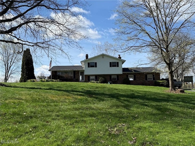 8754 NE Lynnett St NE, Alliance, OH 44601 - view of front facade featuring a front lawn, a chimney, and brick siding