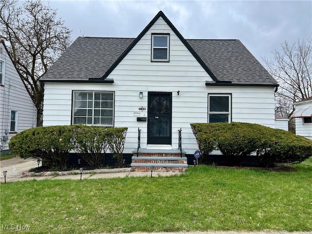 bungalow with roof with shingles, entry steps, and a front yard