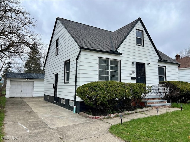 bungalow-style house with driveway, an outbuilding, a detached garage, and a shingled roof