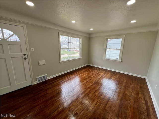 foyer entrance with baseboards, a healthy amount of sunlight, dark wood-type flooring, and visible vents