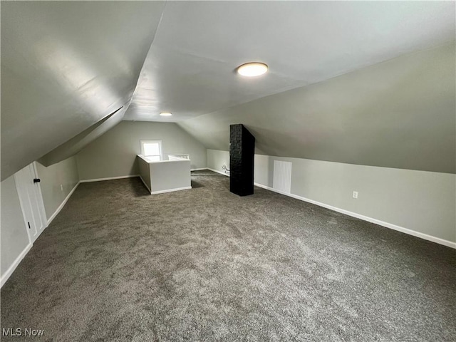 bonus room with dark colored carpet, lofted ceiling, visible vents, and baseboards