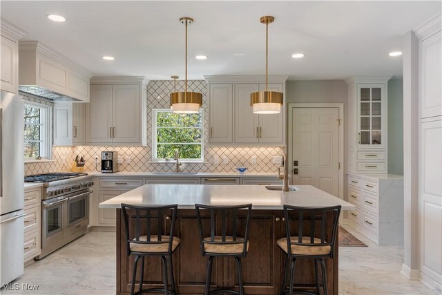 2622 Glenmont Rd NW, Canton, OH 44708 - kitchen with a sink, marble finish floor, stainless steel appliances, a center island with sink, and light countertops