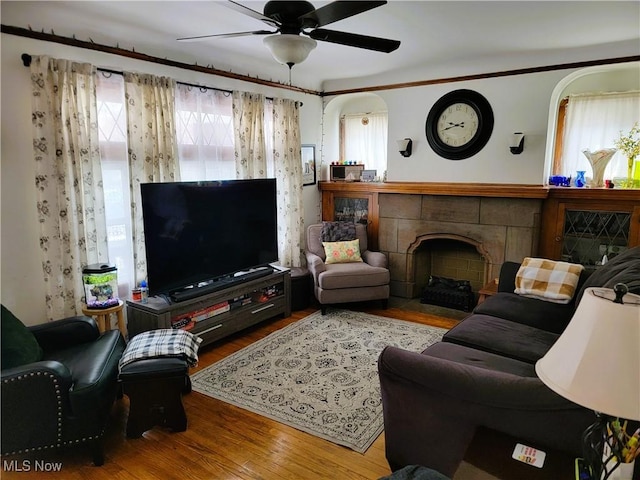 living area with a fireplace, wood finished floors, and a ceiling fan