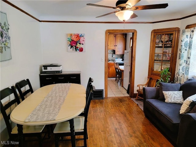 dining room with light wood-type flooring, crown molding, and ceiling fan