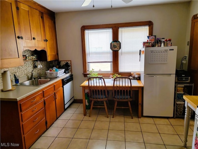 kitchen featuring light countertops, a sink, freestanding refrigerator, decorative backsplash, and dishwasher