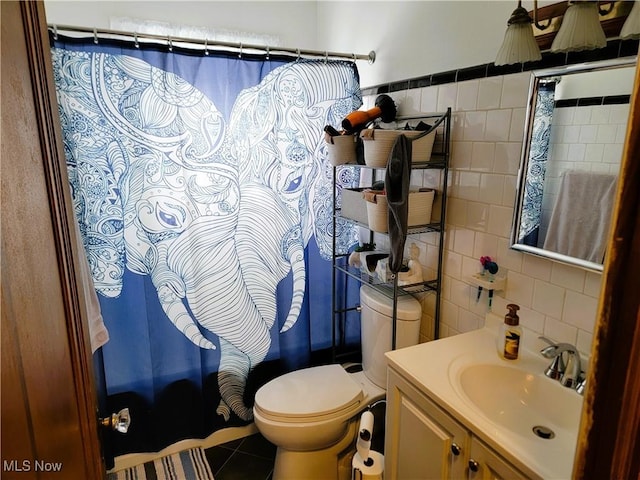 bathroom featuring tile patterned floors, toilet, tile walls, shower / tub combo with curtain, and vanity