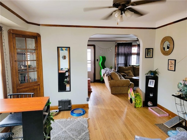 living area with arched walkways, ceiling fan, and a healthy amount of sunlight