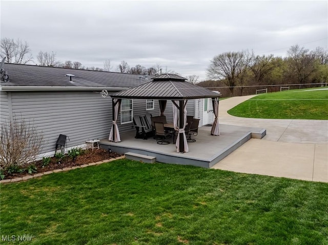 rear view of house featuring a wooden deck, a gazebo, fence, and a yard