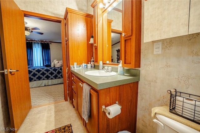 ensuite bathroom with toilet, vanity, a ceiling fan, and connected bathroom