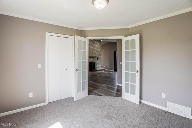empty room with carpet, visible vents, ornamental molding, french doors, and baseboards