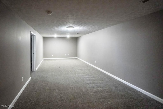 finished basement featuring a textured ceiling, carpet flooring, and baseboards
