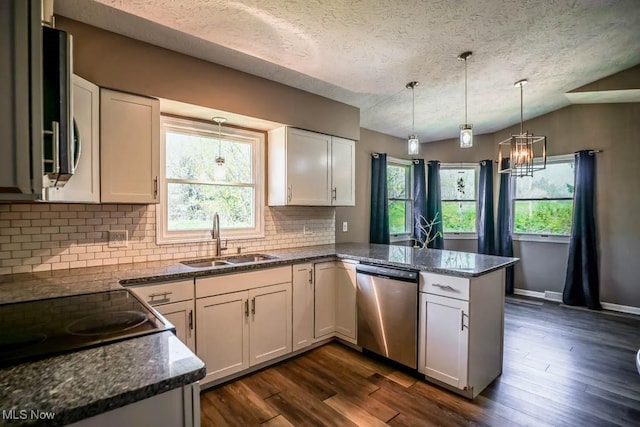 kitchen featuring an inviting chandelier, a sink, a peninsula, a textured ceiling, and appliances with stainless steel finishes