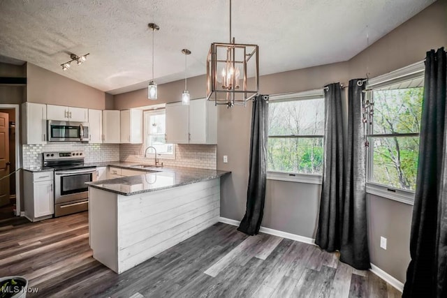 kitchen featuring white cabinets, stainless steel appliances, a sink, tasteful backsplash, and a textured ceiling