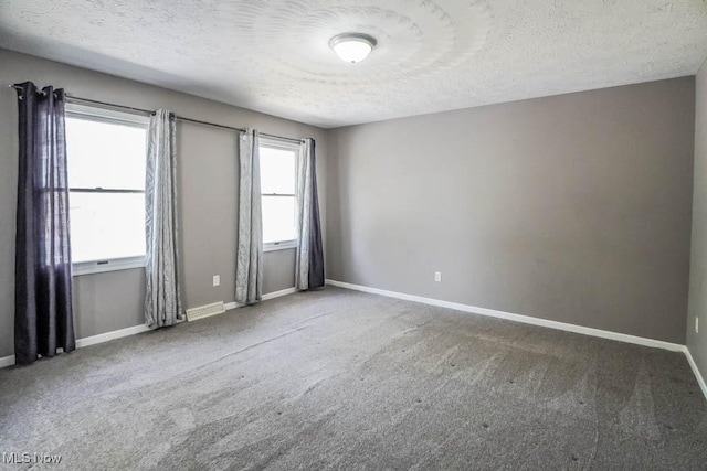 unfurnished room with carpet floors, a textured ceiling, and baseboards