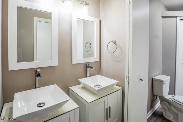 bathroom featuring two vanities, toilet, and a sink