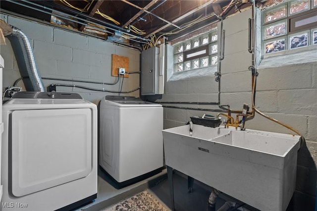 laundry area with electric panel, concrete block wall, washer and dryer, and laundry area