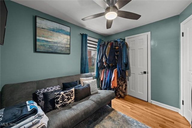 living area featuring baseboards, a ceiling fan, and wood finished floors