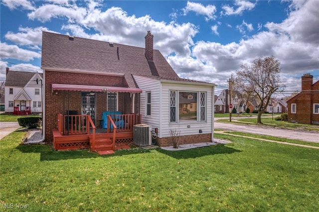 back of house featuring roof with shingles, central air condition unit, a chimney, a wooden deck, and a yard