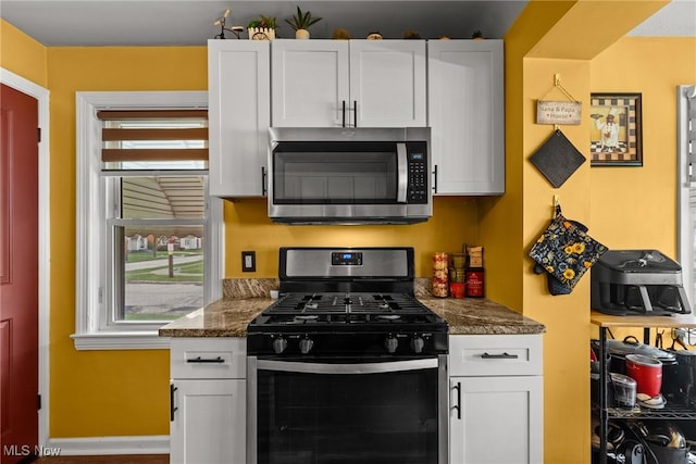 kitchen with white cabinets, dark countertops, baseboards, and appliances with stainless steel finishes