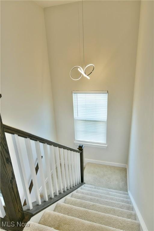 staircase with baseboards and a chandelier