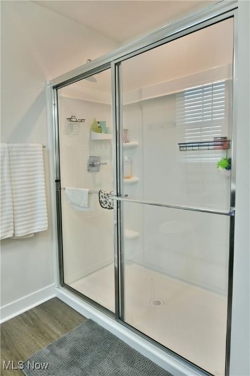bathroom featuring baseboards, wood finished floors, and a stall shower