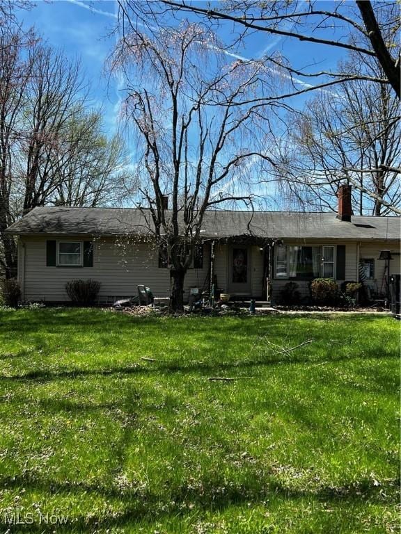 single story home featuring a chimney and a front yard