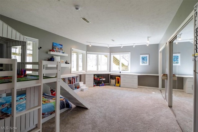 carpeted bedroom with a textured ceiling and track lighting