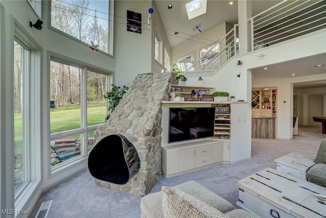 living room featuring carpet floors, a towering ceiling, and a skylight