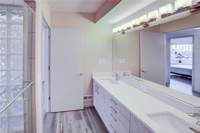 ensuite bathroom with wood finished floors, a stall shower, and double vanity