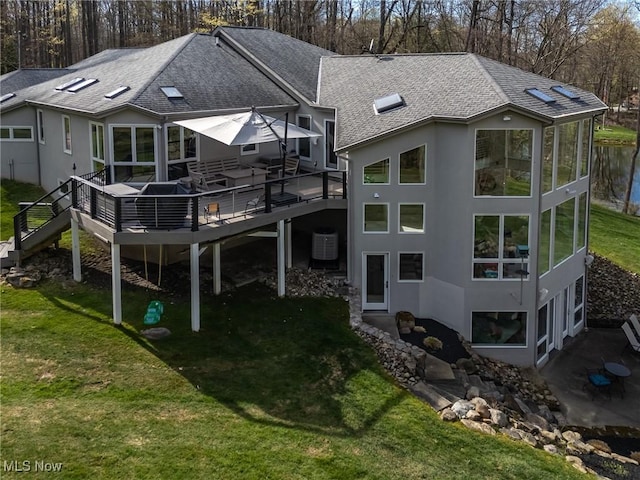 back of house featuring central air condition unit, a wooden deck, roof with shingles, a yard, and stairway
