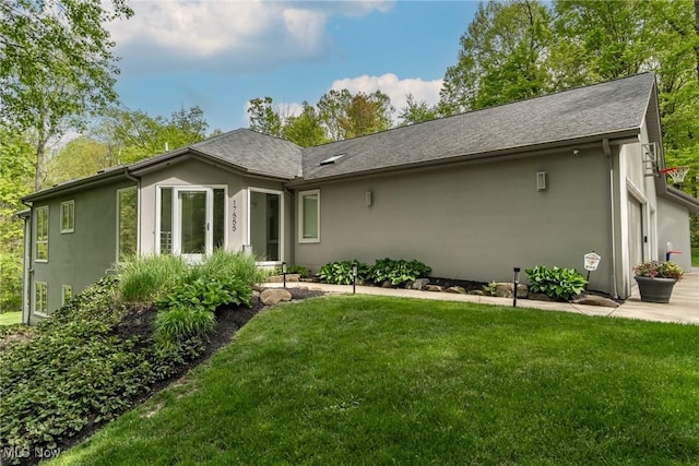 rear view of house with stucco siding and a yard