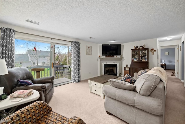 living room with light carpet, a textured ceiling, visible vents, and a fireplace